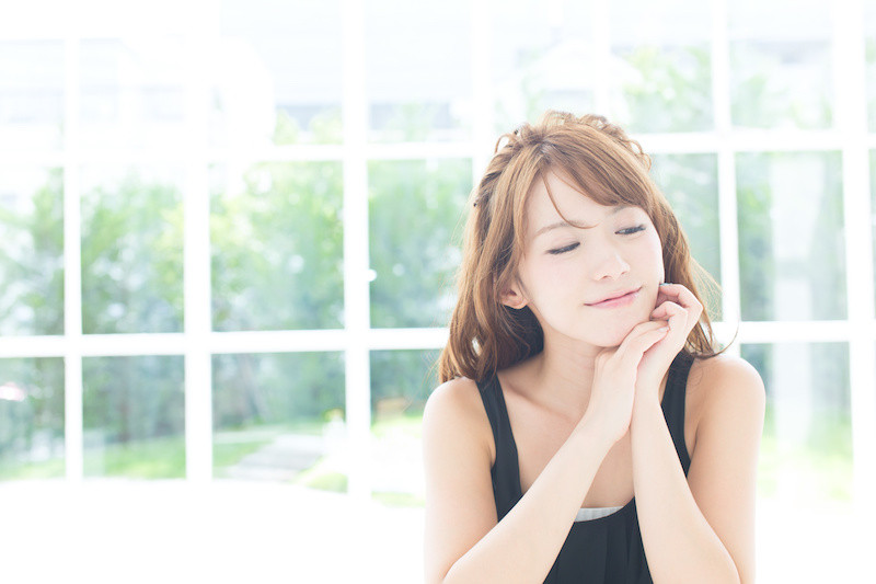 大きい窓からたくさん光が入ってくる部屋でくつろいでいる女性